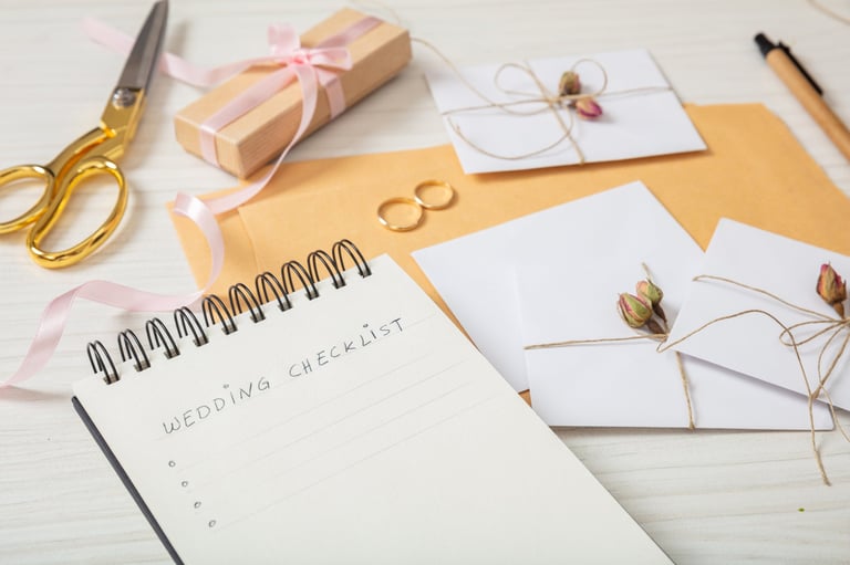 Wedding preparation flat lay and close up view of checklist and wedding invitations on white wooden tabletop — Wedding Checklist tool Tanzania