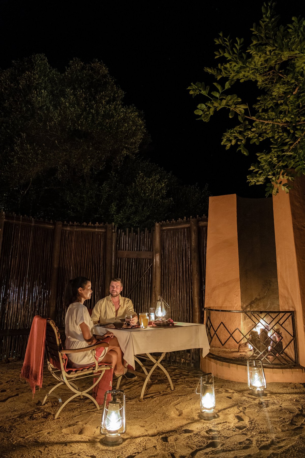 Couple enjoying a private candlelit dinner in the bush at a luxury safari lodge at night