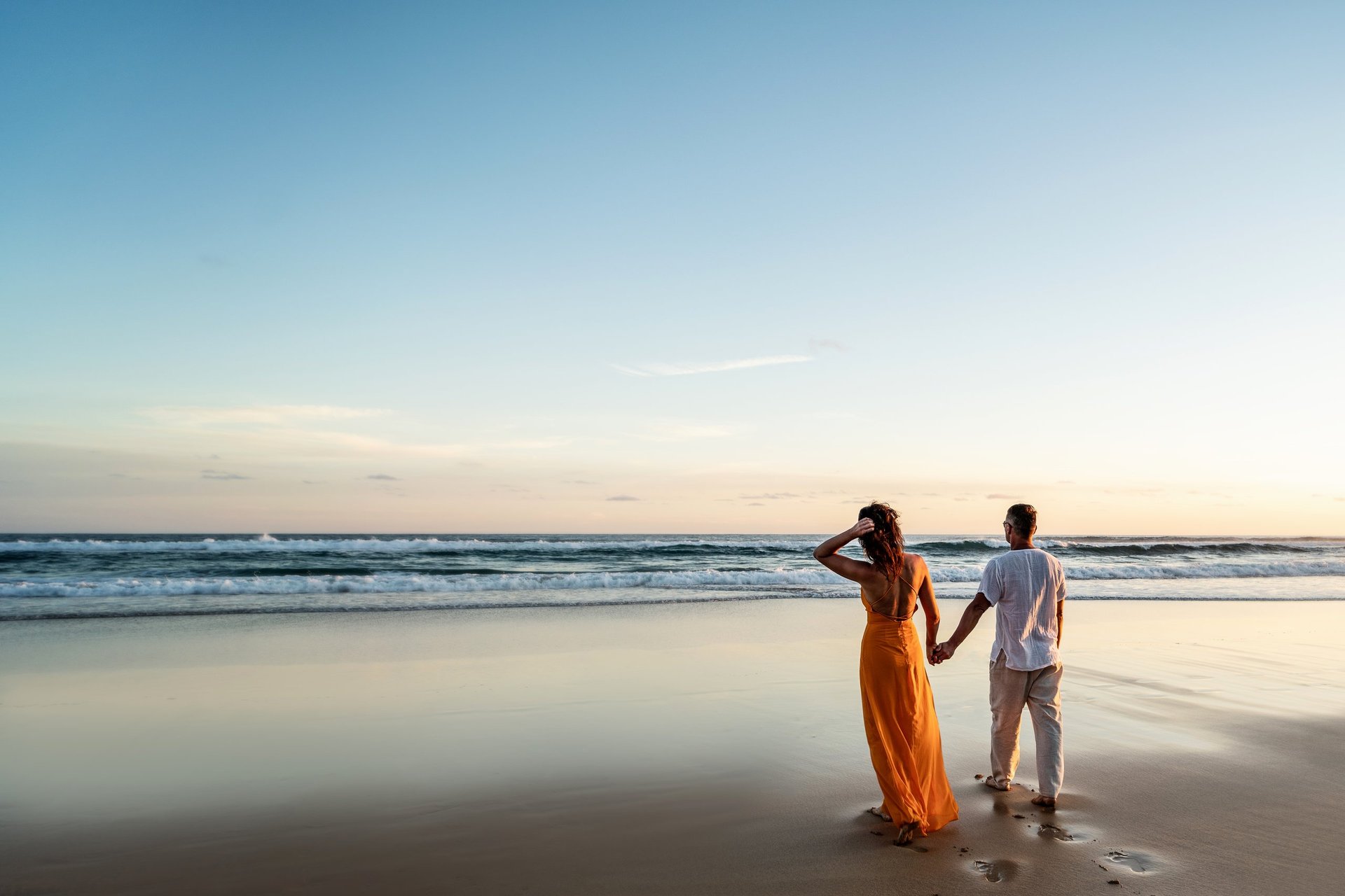 Romantic couple walking on a sunset beach in warm evening light during a tropical honeymoon
