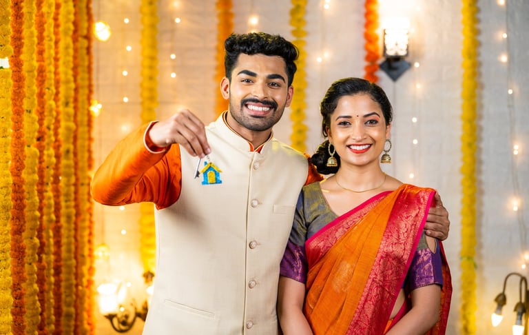 Happy young indian couple showing new home keys by looking at camera