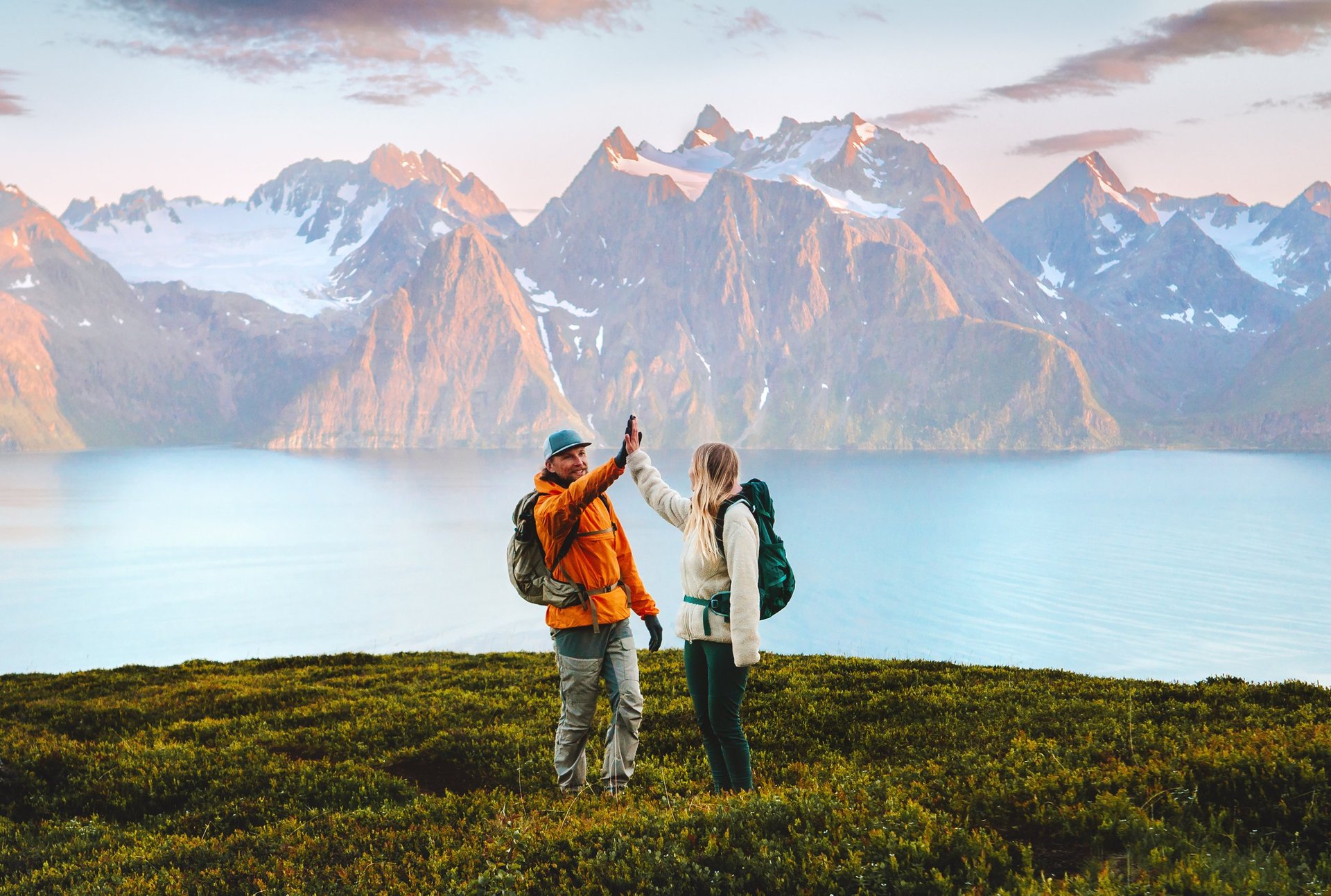 Adventurers high-fiving on a mountain top after a challenging climb, celebrating outdoors