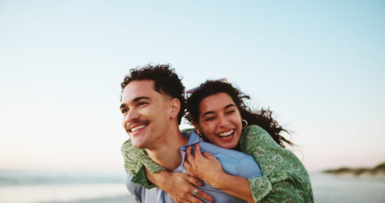 Couple laughing and embracing at the beach for a romantic vacation