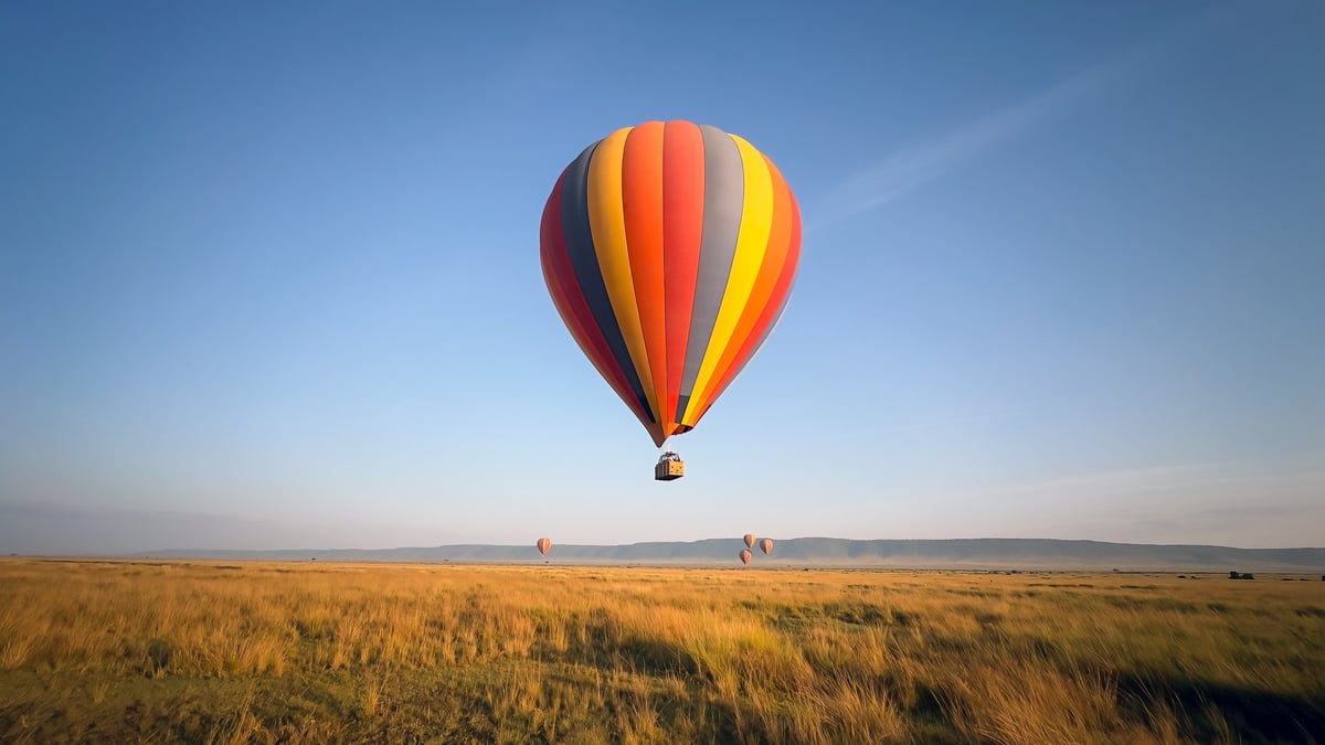 Hot air balloon floating over the Serengeti savanna at sunrise