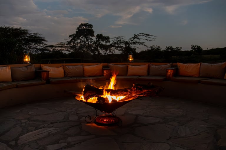 Cozy fire pit burning at dusk in a luxury safari lodge outdoor lounge