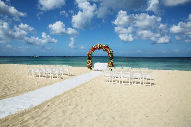 Beautiful Beach Wedding Ceremony Setup with Floral Arch, White Chairs, and Ocean View
