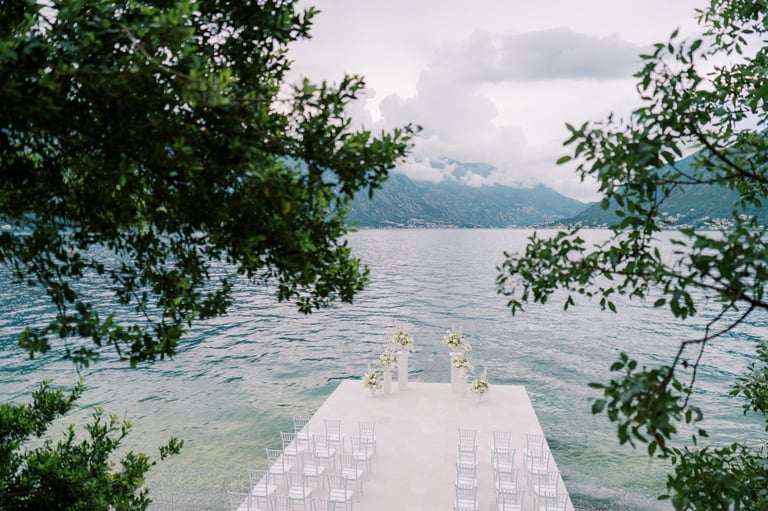 Lakeside wedding aisle with white chairs and floral arch at Kigoma Lake Tanganyika with mountains and water view