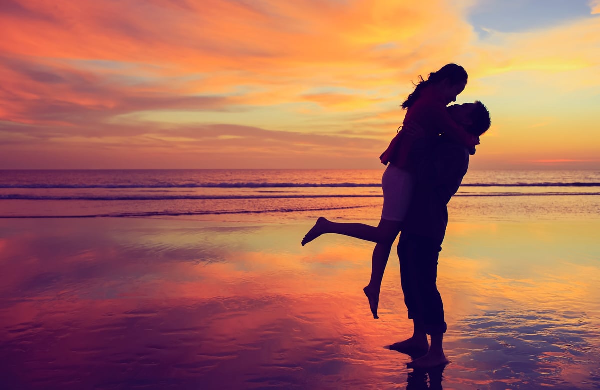 Happy couple kissing and hugging captured in a sunset background