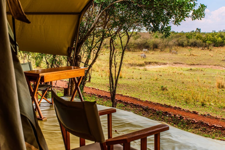 Veranda of an exclusive luxury safari tent overlooking grazing zebra in the distance