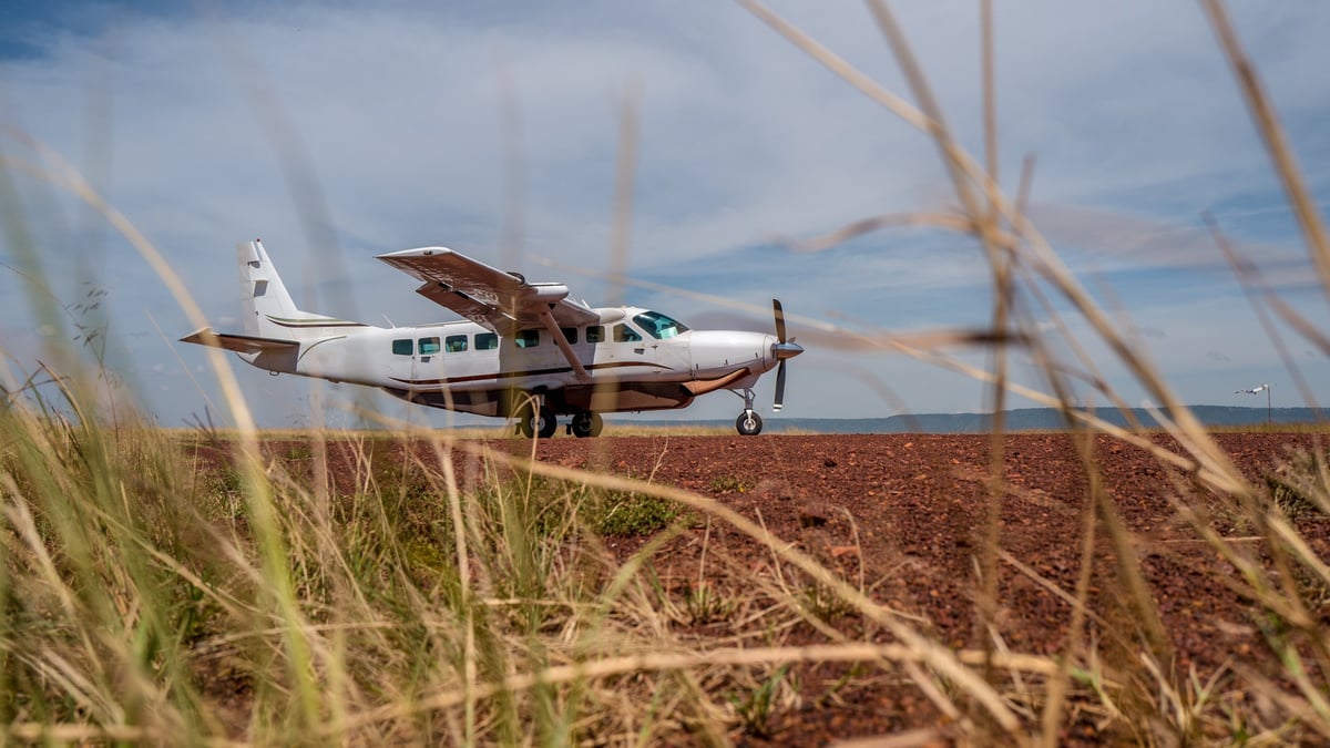 Light aircraft on a dirt airstrip in the Masai Mara savanna, the kind used for Zanzibar to Serengeti fly-in safaris