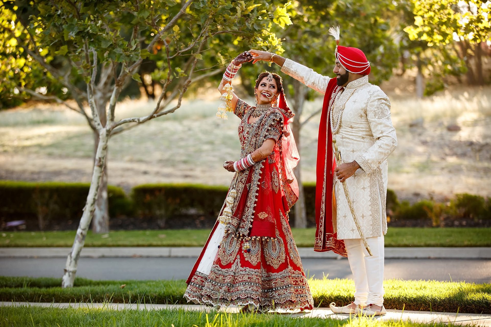 Cinematic Wedding Videography Tanzania — Bride and groom in traditional Indian wedding attire pose together outdoors with trees in background, luxury wedding film production Dar es Salaam