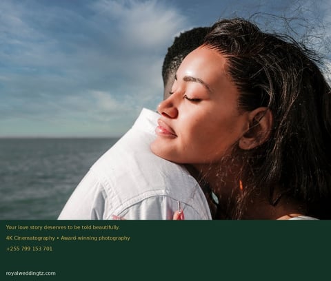 Woman with long dark hair leaning against a man in white shirt, ocean and sky visible in background