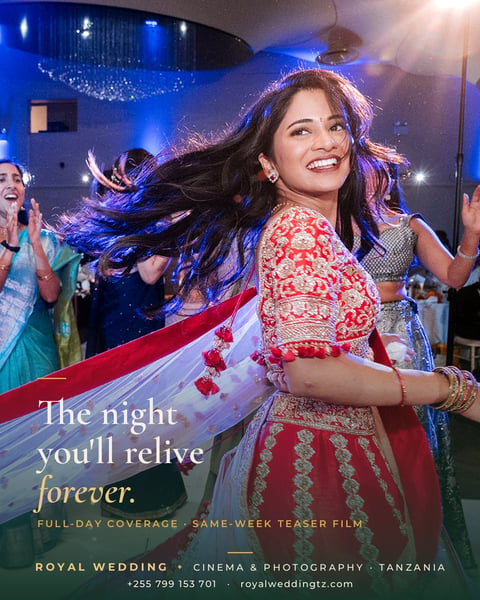 Woman in red and white traditional wedding attire dancing at a blue-lit celebration with guests clapping in background