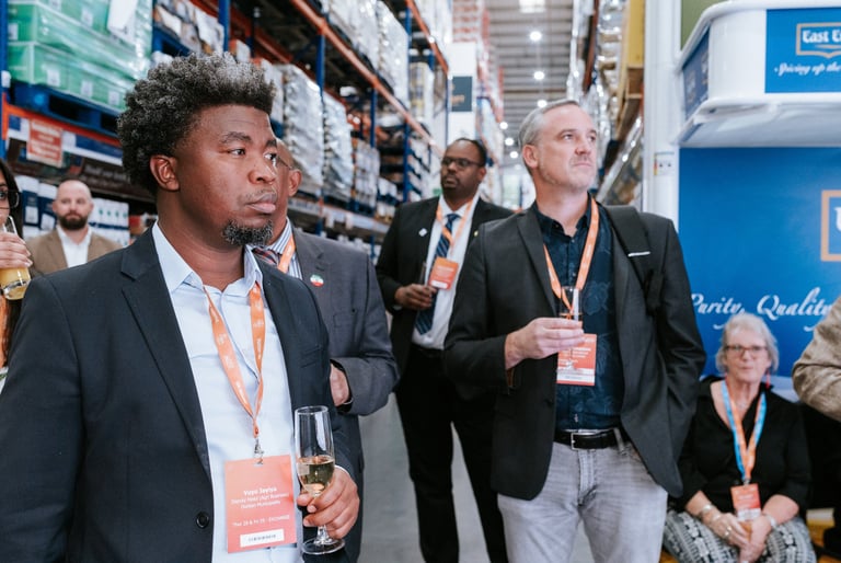Corporate conference photography — business professionals wearing ID badges at trade show event inside retail store setting, Dar es Salaam Tanzania