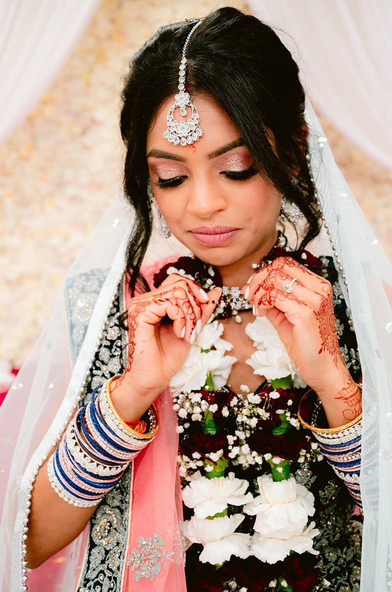 Hindu bride in traditional South Asian wedding attire with ornate gold jewelry, intricate henna, red veil and white floral bouquet — Hindu wedding photographer Dar es Salaam Tanzania