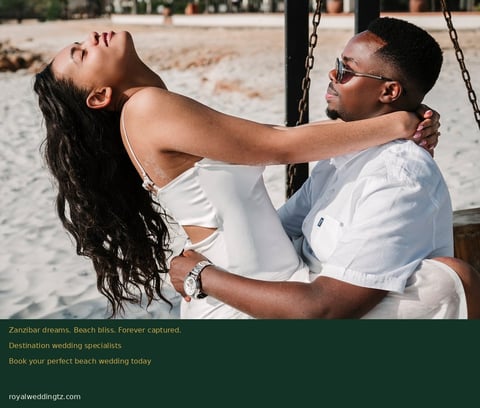 Couple embracing on beach swing, man in white shirt and glasses, woman in white top with long dark hair
