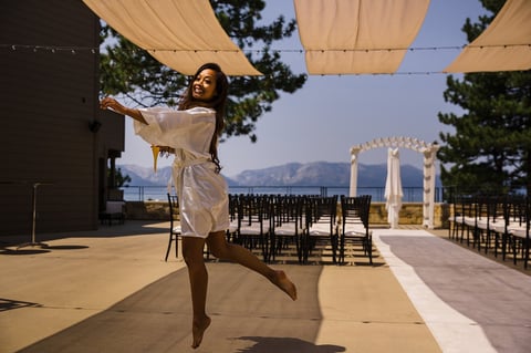 Woman in white dress twirling at an outdoor wedding venue with mountains visible in the background