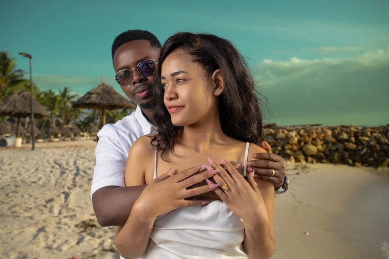 Couple embracing on a tropical beach with clear sky and palm trees in the background