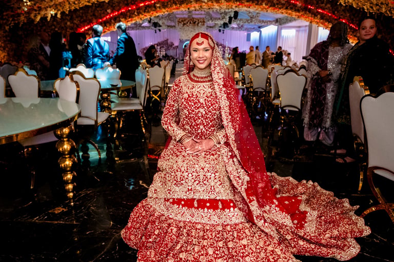 Bride in red ornate lehenga posing in decorated wedding hall with guests and tables — luxury Asian wedding photographer Tanzania Dar es Salaam by Royal Wedding Cinema & Photography