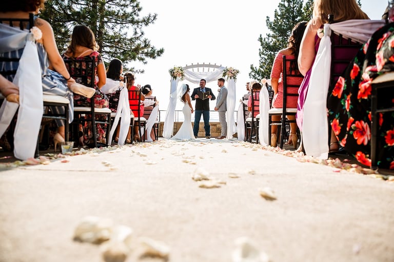 Bride and groom walking through fabric-lined aisle at outdoor beach wedding ceremony with guests seated on both sides