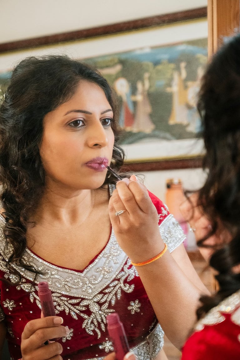 Bridal Preparation Wedding Film — Bride applying lipstick while looking in mirror, wearing red embroidered traditional dress
