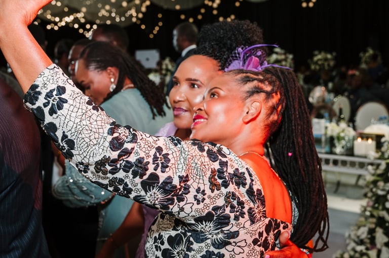 Two women dancing together at a nighttime outdoor event with string lights and greenery in the background