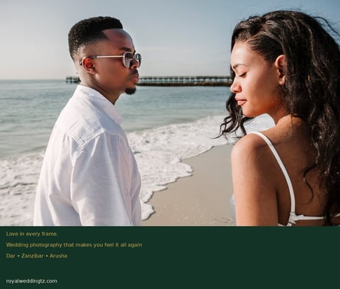 Couple smiling at each other on a beach with ocean waves and pier in background