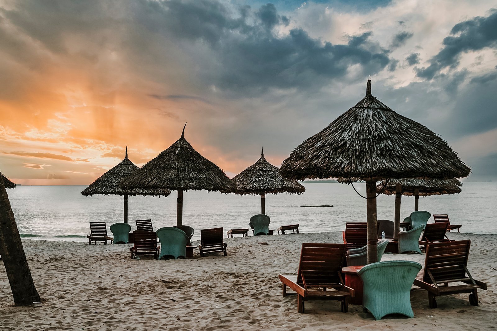 White Sands Hotel — Beach resort with thatched umbrellas, lounge chairs, and calm sea during golden sunset