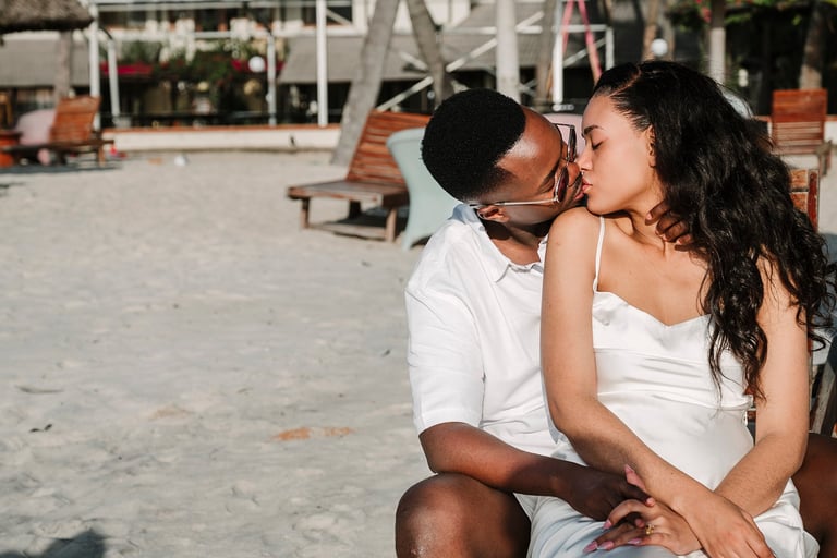 Couple kissing on a sandy beach near a wooden pier and boats