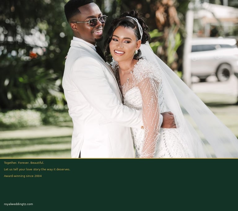 Newlywed couple in white formal attire posing together outdoors in a garden setting on their wedding day