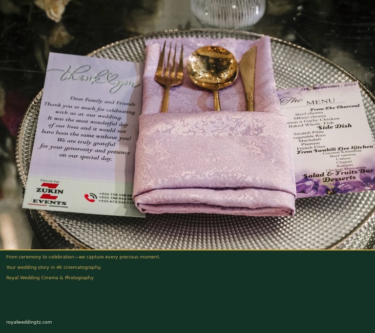 Wedding table place setting with gold flatware, pink napkin, thank you card, and menu on white plate