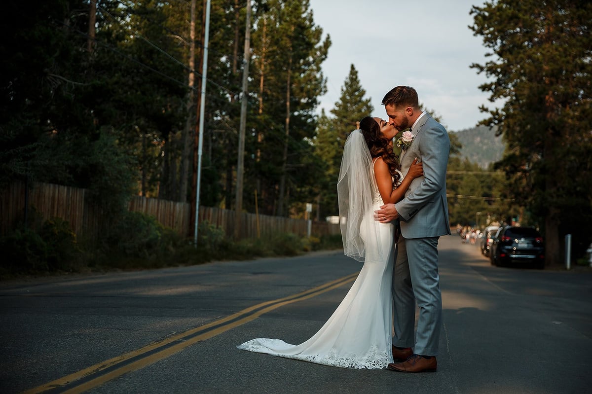 Bride and groom sharing a romantic kiss on a forested mountain road, cinematic wedding couple portrait in Tanzania