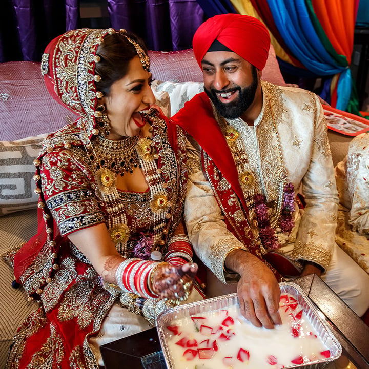 Tanzanian couple in traditional wedding attire during Mehendi ceremony with vibrant colorful fabric backdrop