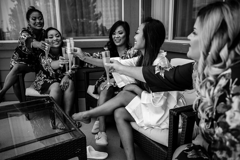 Group of women toasting with drinks at an indoor gathering, black and white photograph