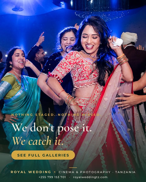 Bride in pink embellished lehenga dancing with guests at wedding celebration under blue lighting