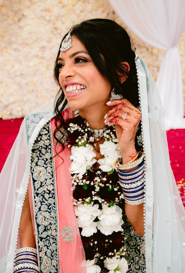Fusion wedding film Tanzania — Radiant Indian bride in traditional bridal attire with ornate gold jewelry, white veil, and floral garland, cross-cultural wedding videography Dar es Salaam