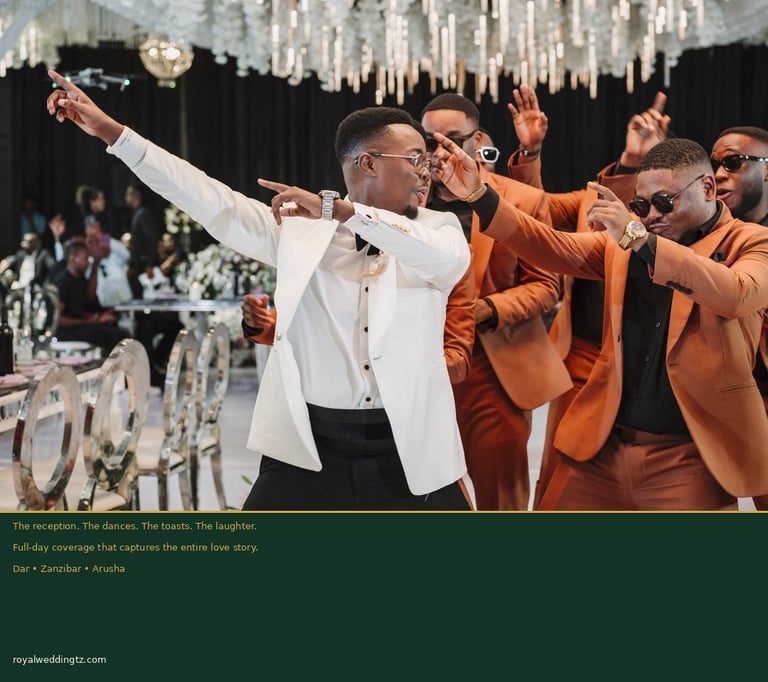 Man in white tuxedo and three men in orange suits celebrating at an elegant event with chandelier and formal decor