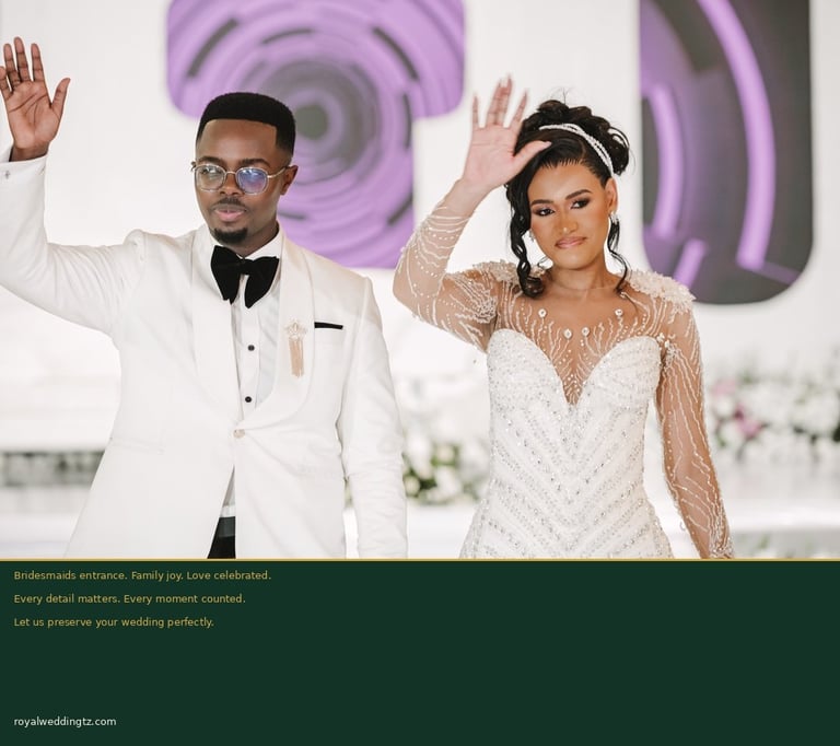 Bride and groom waving at wedding reception with purple decorative backdrop and white floral arrangements