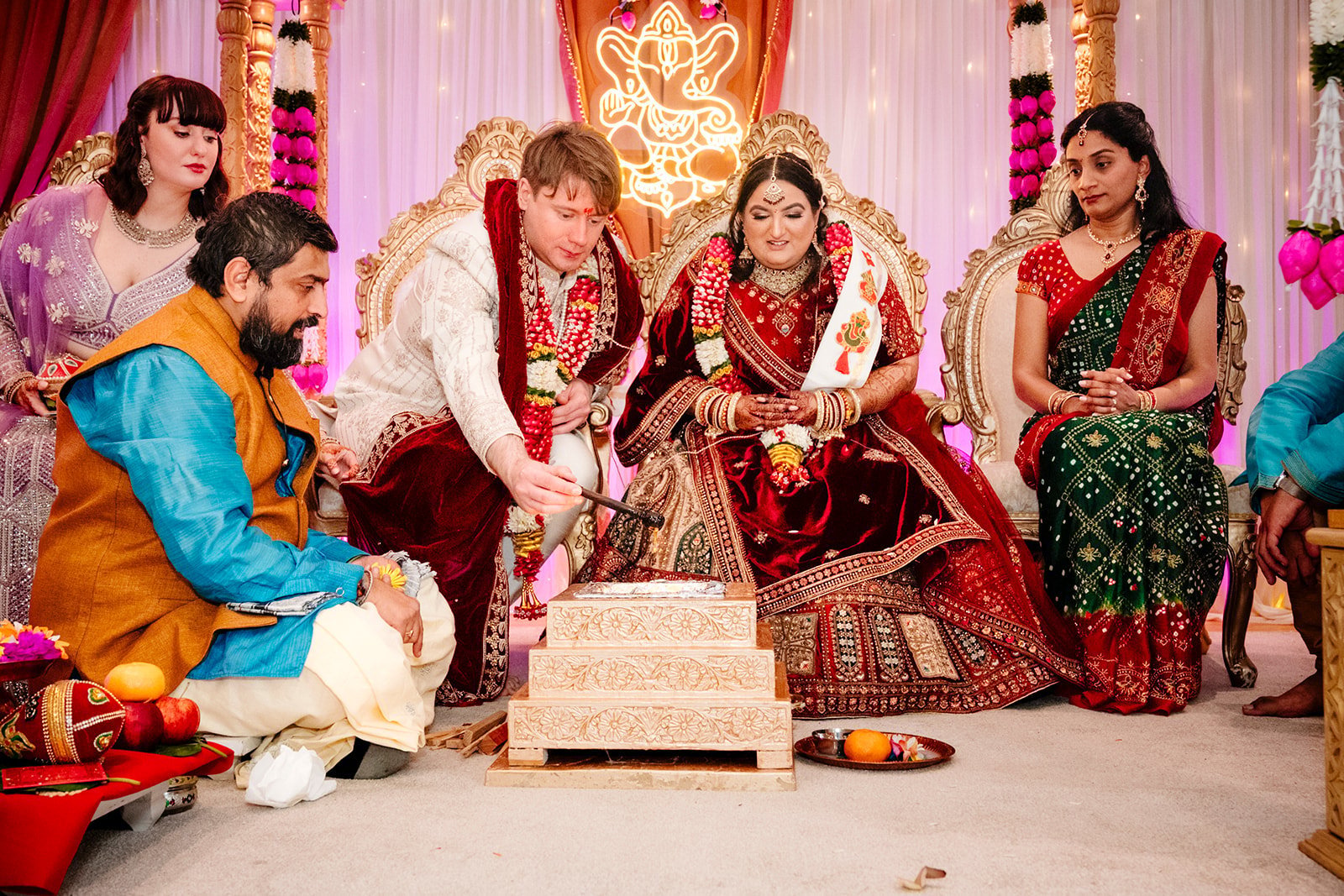 Hindu wedding ceremony with bride and groom in traditional red and gold attire performing sacred ritual at decorated venue with golden mandap — Hindu wedding photography Tanzania
