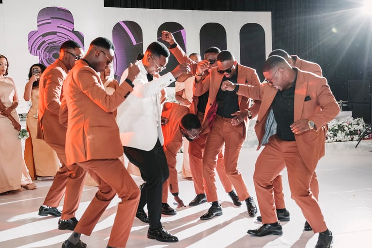 Group of people in coordinated orange suits dancing together on a stage at an event