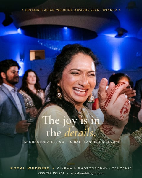 Woman with henna-adorned hands smiling at an Asian wedding celebration with blue ambient lighting and guests in formal attire