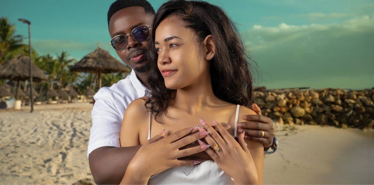 Couple embracing on a tropical beach with palm trees and clear blue sky in background