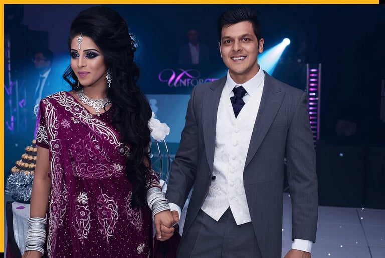 Elegantly dressed couple holding hands at a formal event with stage lighting in the background