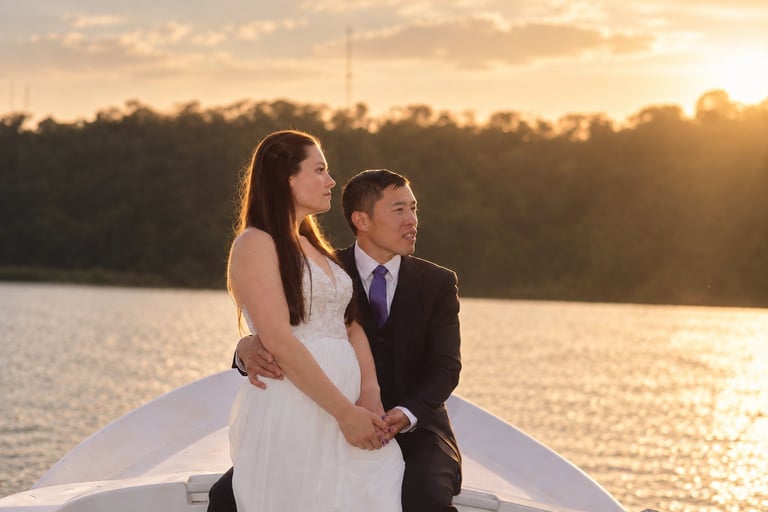Bride and groom holding hands on a boat at sunset over water